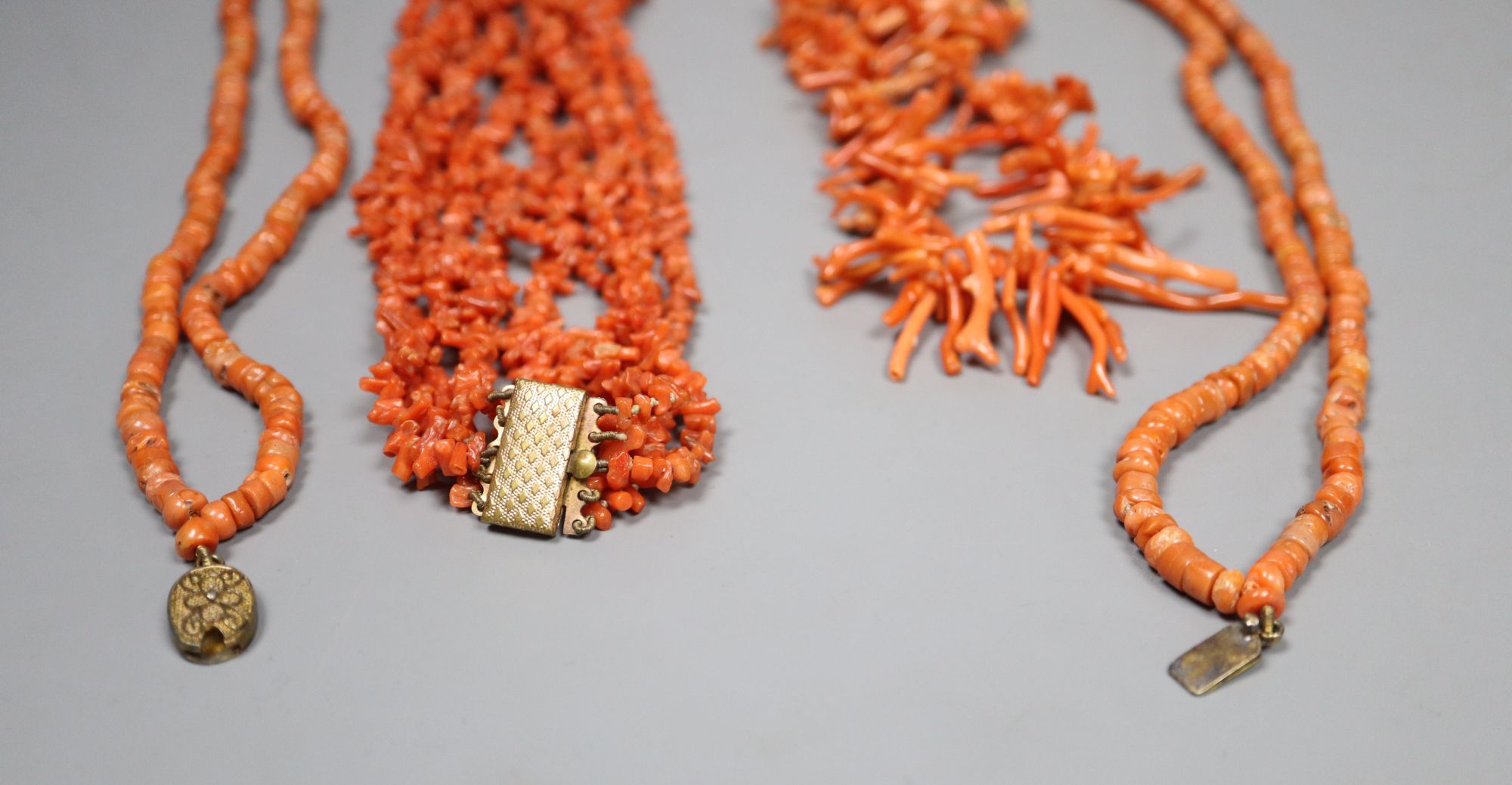 Three assorted coral necklaces including bead and fragment, with gilt metal clasps, longest 62cm, gross weight 153 grams.